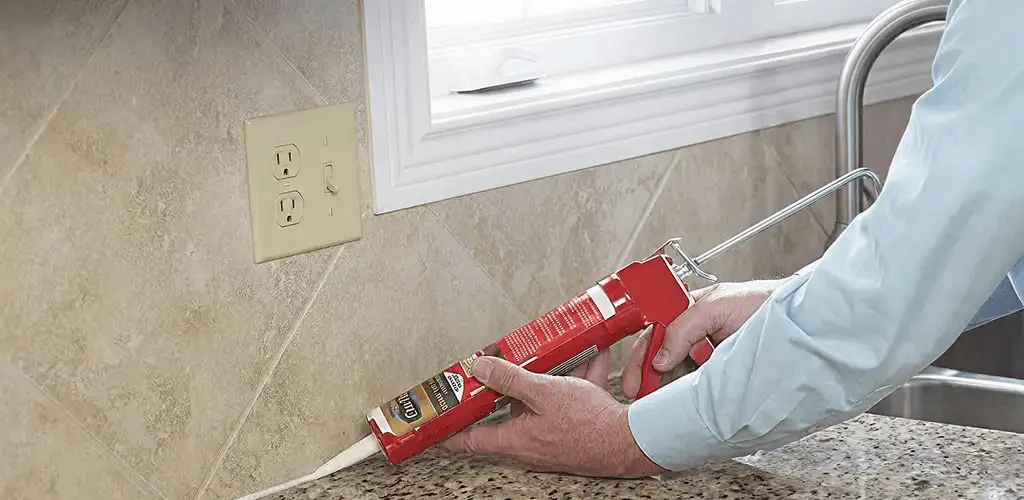 Handyman applying caulk along a kitchen backsplash and countertop seam in Lincoln, NE