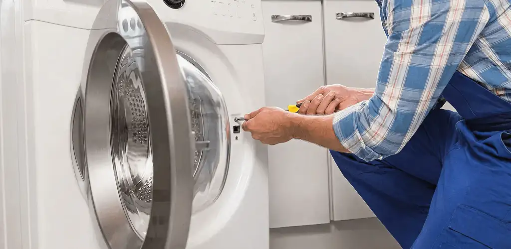 Handyman repairing a clothes dryer and checking electrical connections in Lincoln, NE
