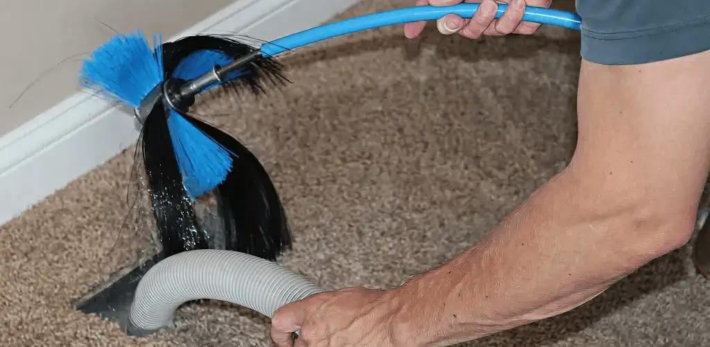 Dryer vent cleaning technician brushing lint from a vent line in Lincoln, NE