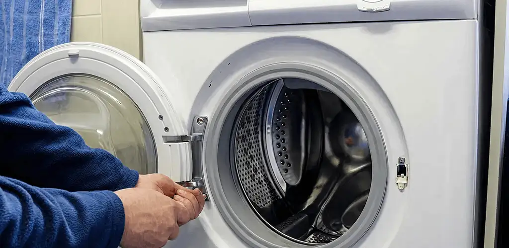 Washing machine repair handyman checking a front-load washer door and latch in Lincoln, NE