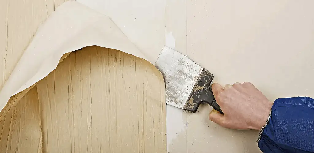 Handyman removing wallpaper with a scraper for wall preparation in Lincoln, NE
