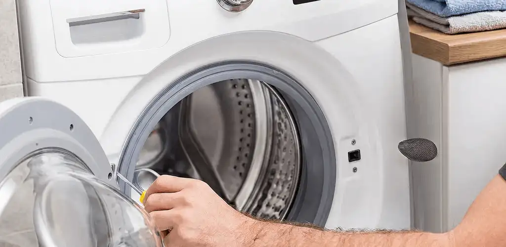 Handyman repairing a front-load washing machine and inspecting the drum in Lincoln, NE