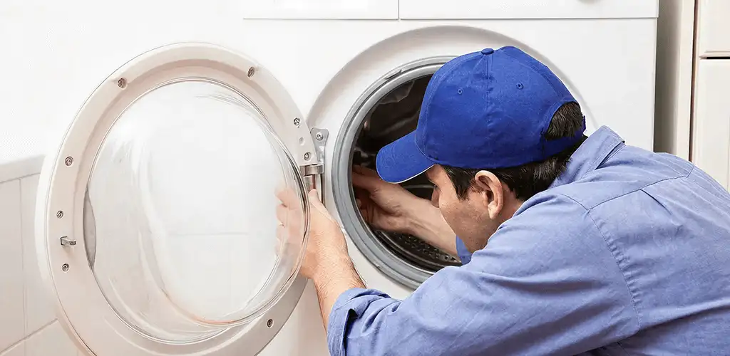 Washing machine repair handyman inspecting a front-load washer drum in Lincoln, NE