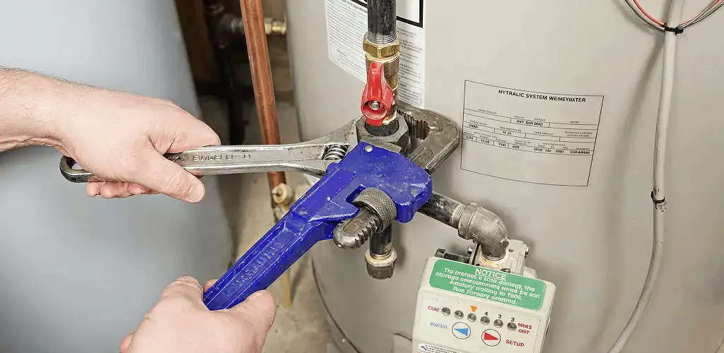 Water heater repair technician tightening the shutoff valve and supply line in Lincoln, NE